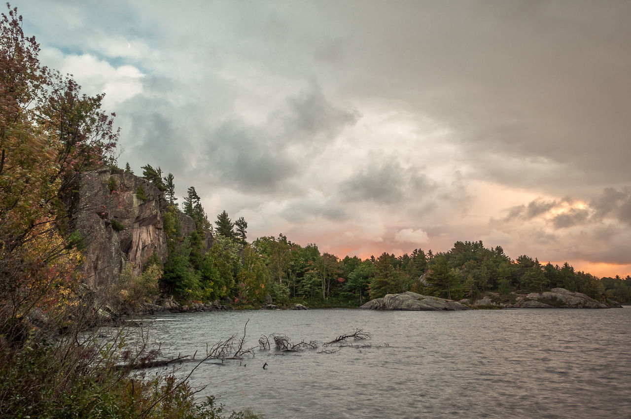 CALM COUNTRYSIDE LAKE AGAINST CLOUDY SKY