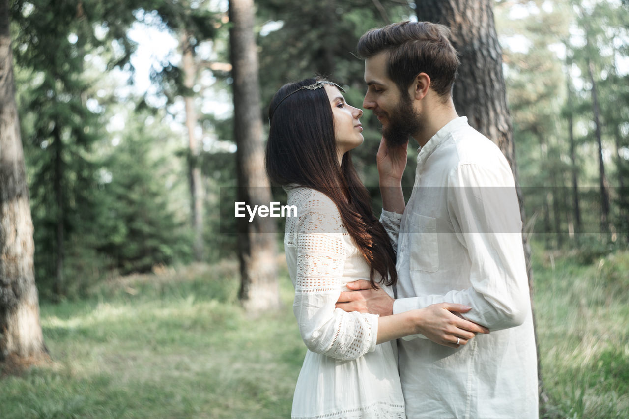 Romantic couple embracing while standing in forest