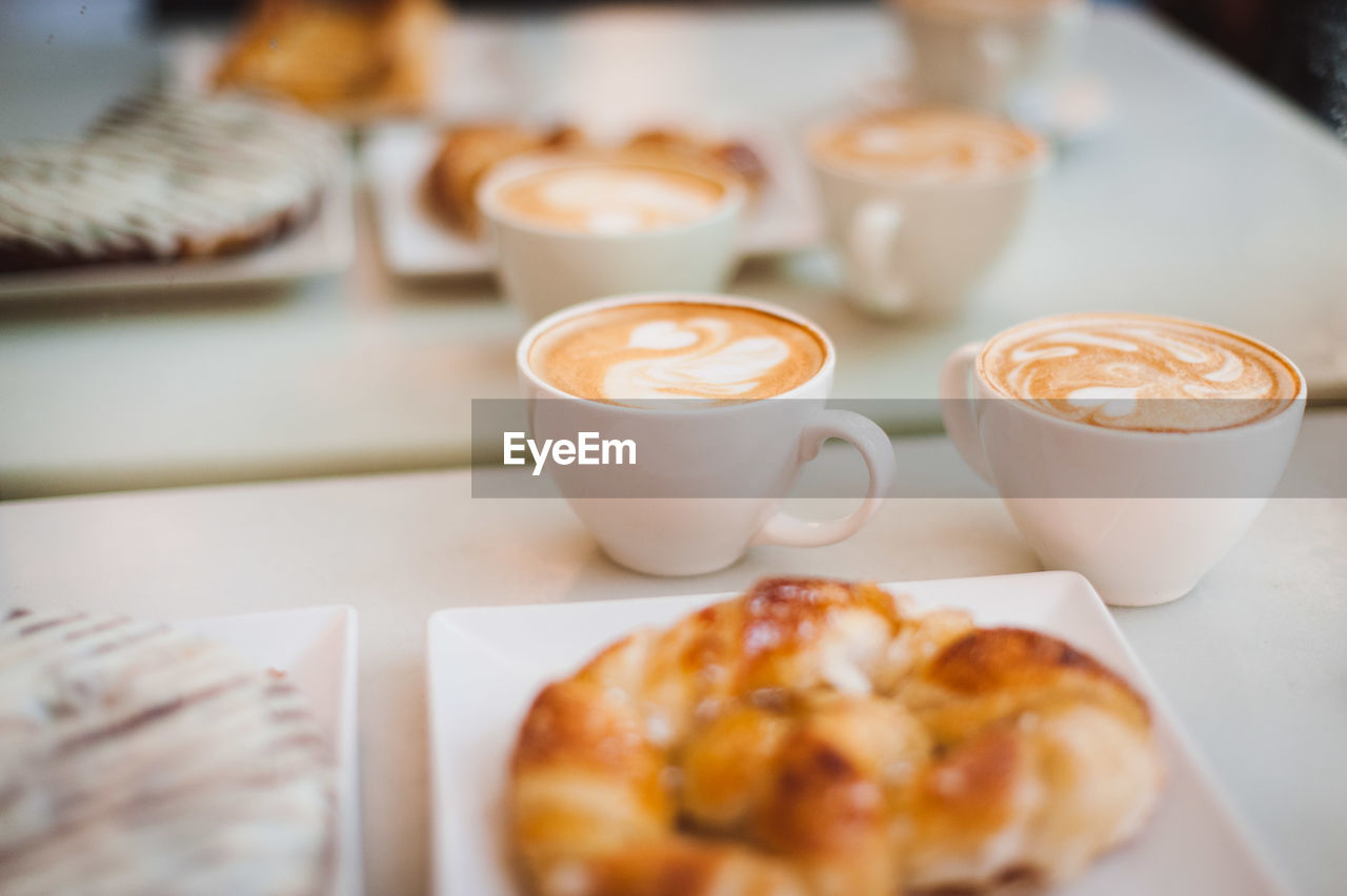 High angle view of cappuccinos with croissants served on table