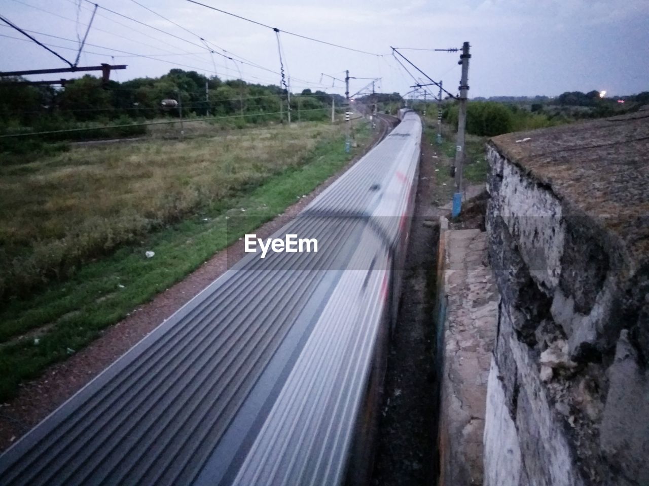 RAILROAD TRACK ON FIELD AGAINST SKY