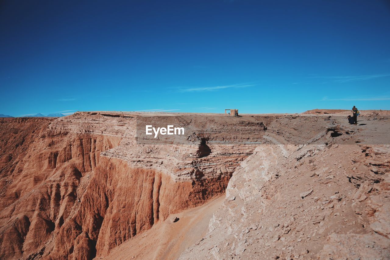 Friends standing on cliff against blue sky