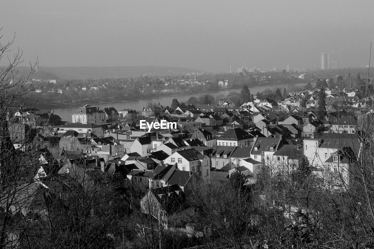 Houses by river in town against sky