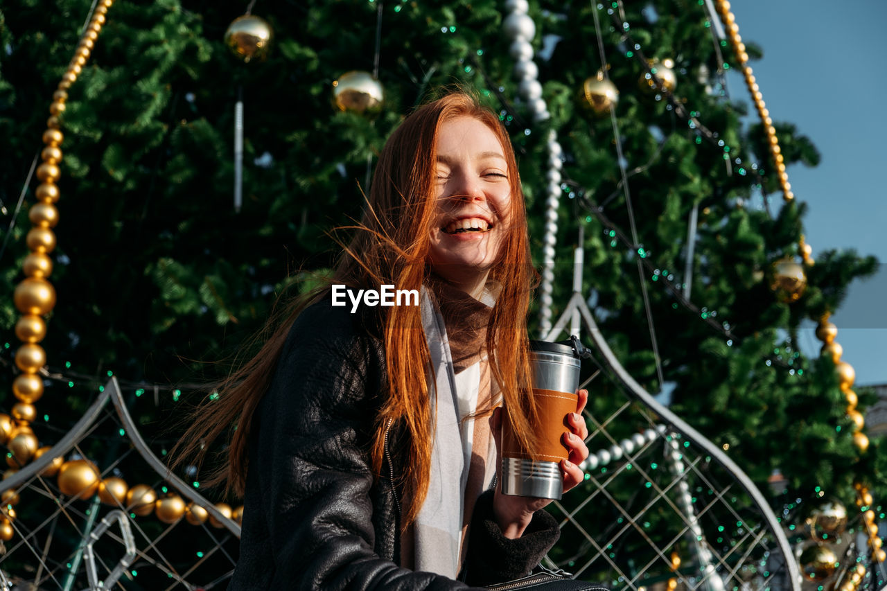 Portrait of smiling young woman against trees