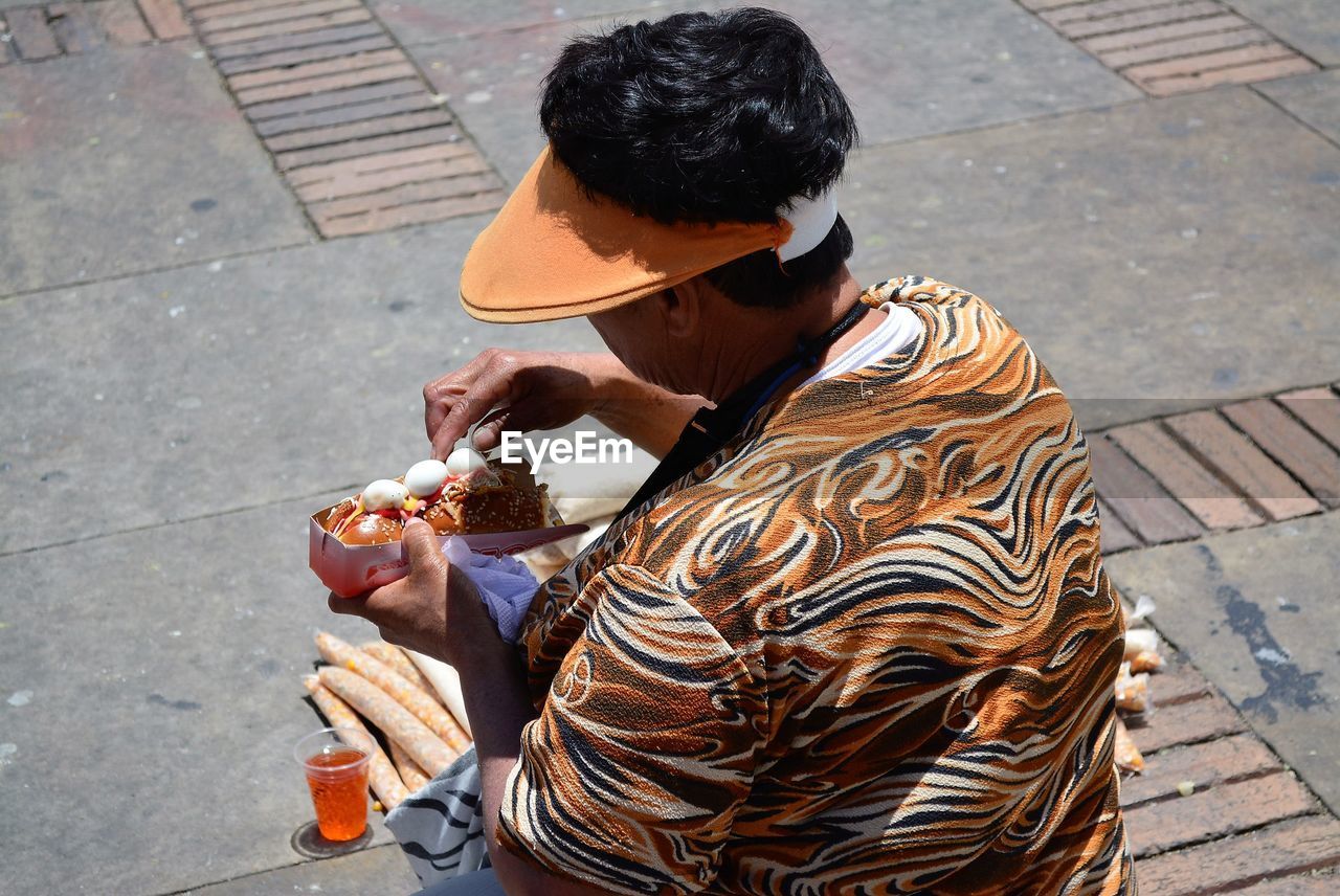 High angle view of man eating hot dog on footpath