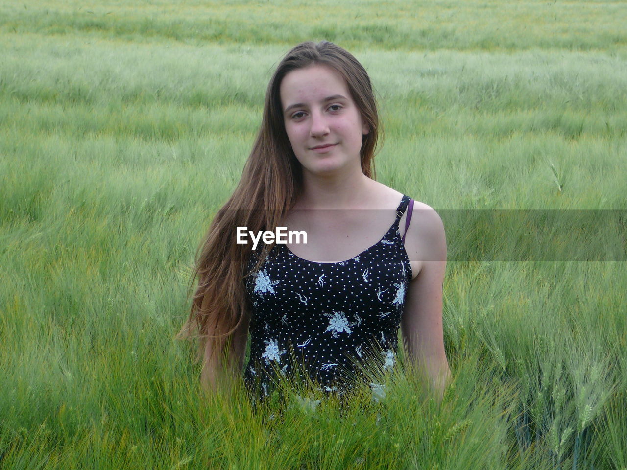 PORTRAIT OF A TEENAGE GIRL STANDING IN FIELD