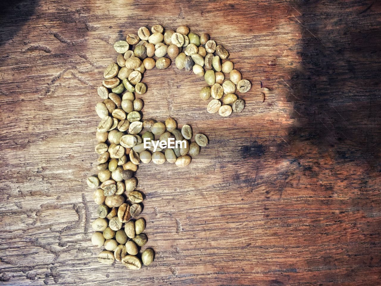 High angle view of carving coffee beams f letter on table
