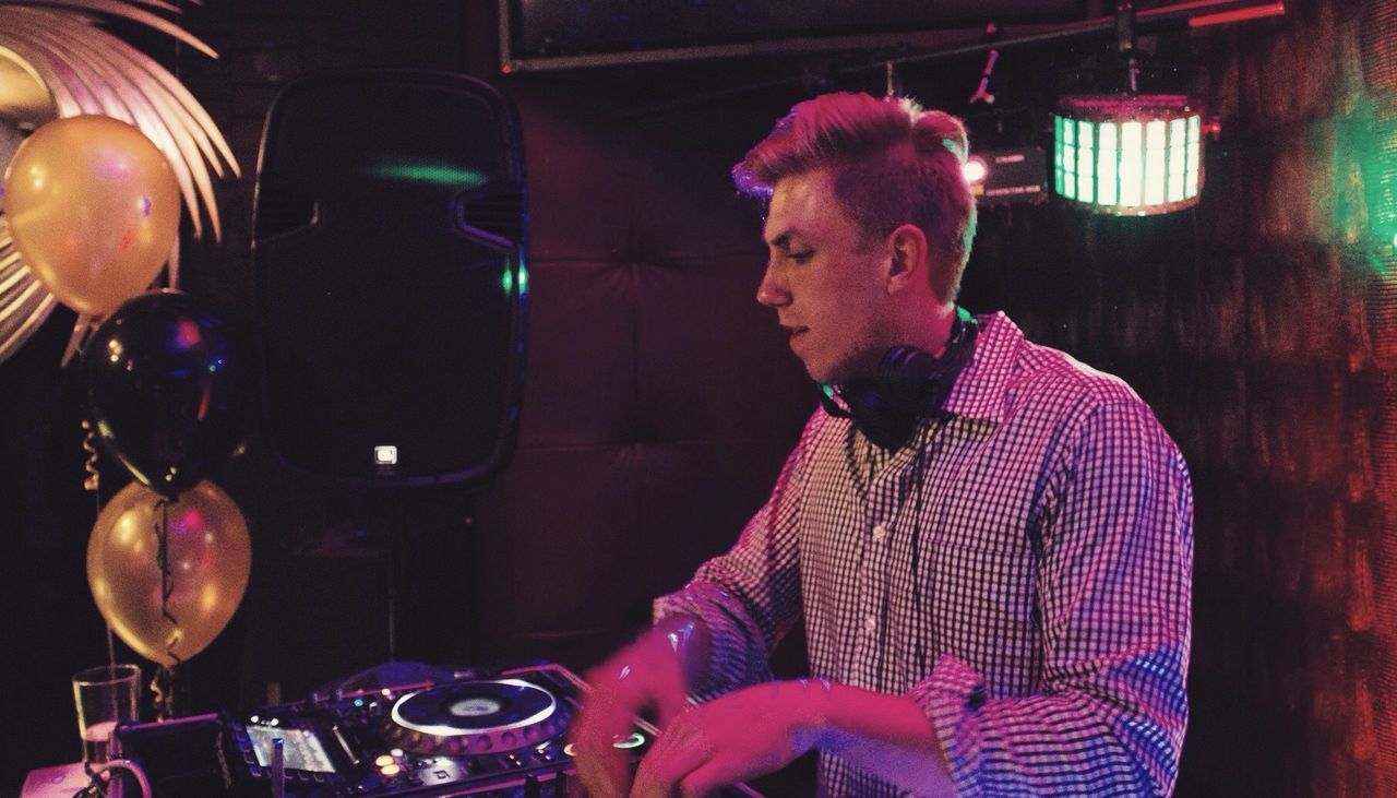 Young male dj mixing sound at nightclub