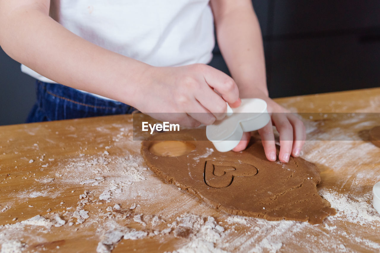 A little girl makes heart-shaped cookies from rye dough. the concept of valentine's day