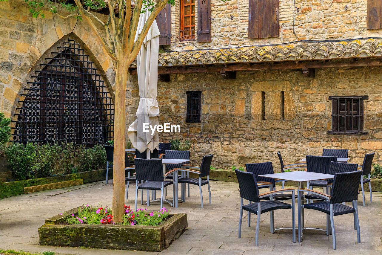 empty chairs and tables in front of old house