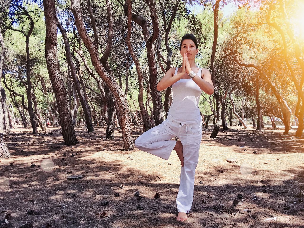 Full length of woman practicing yoga against trees in forest