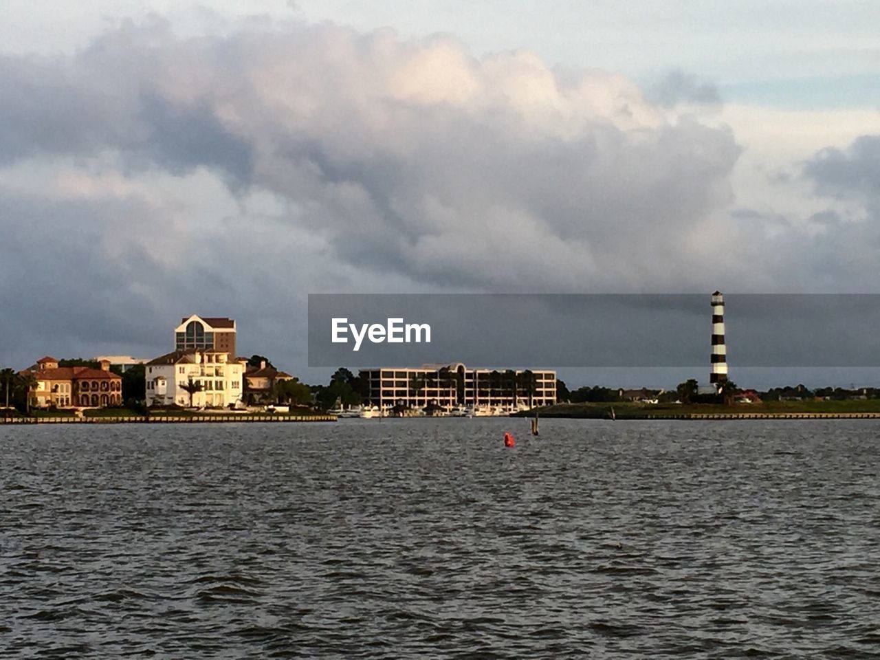 River in front of buildings and lighthouse against cloudy sky at bal harbor