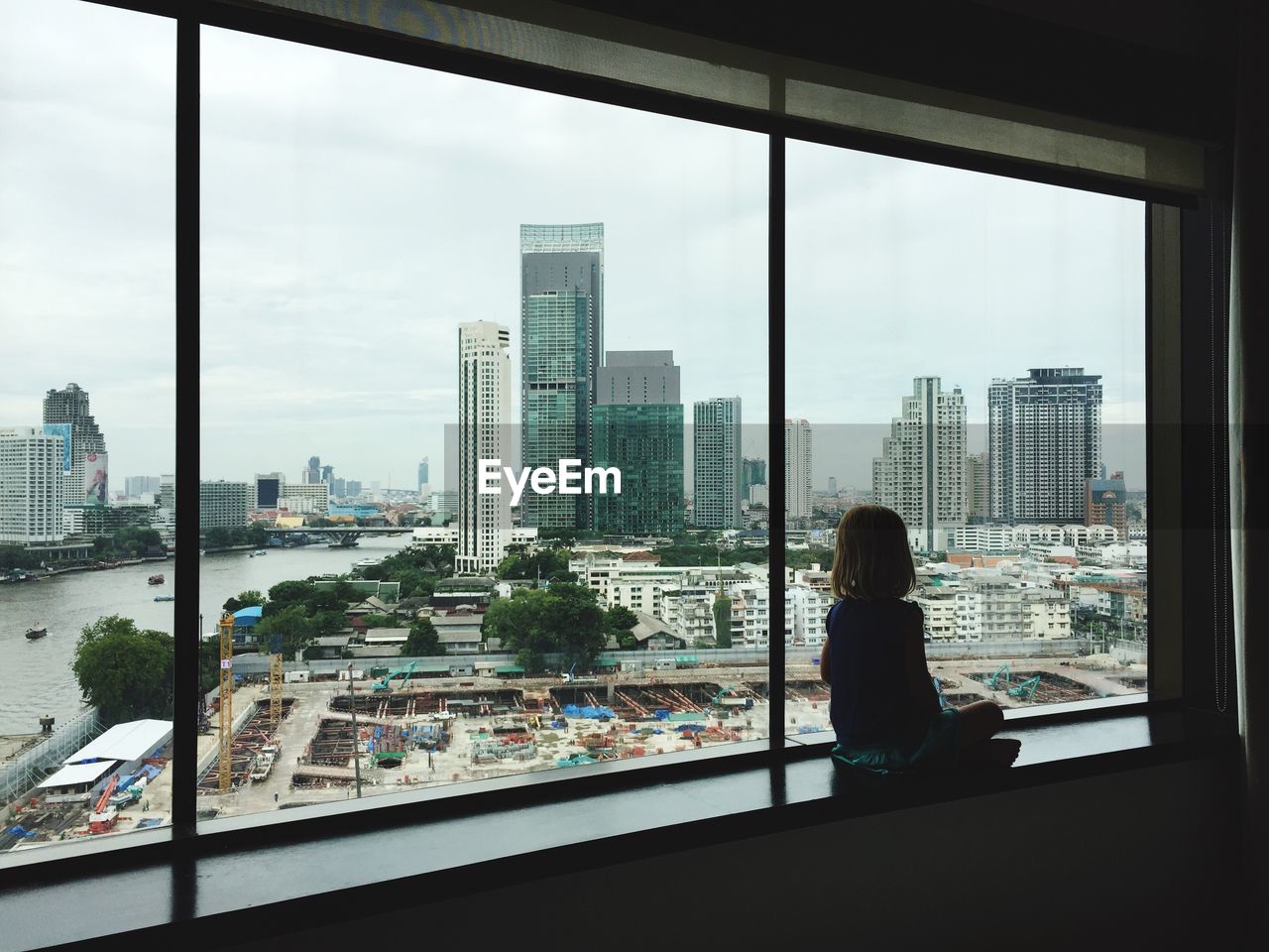 Girl sitting by window in city