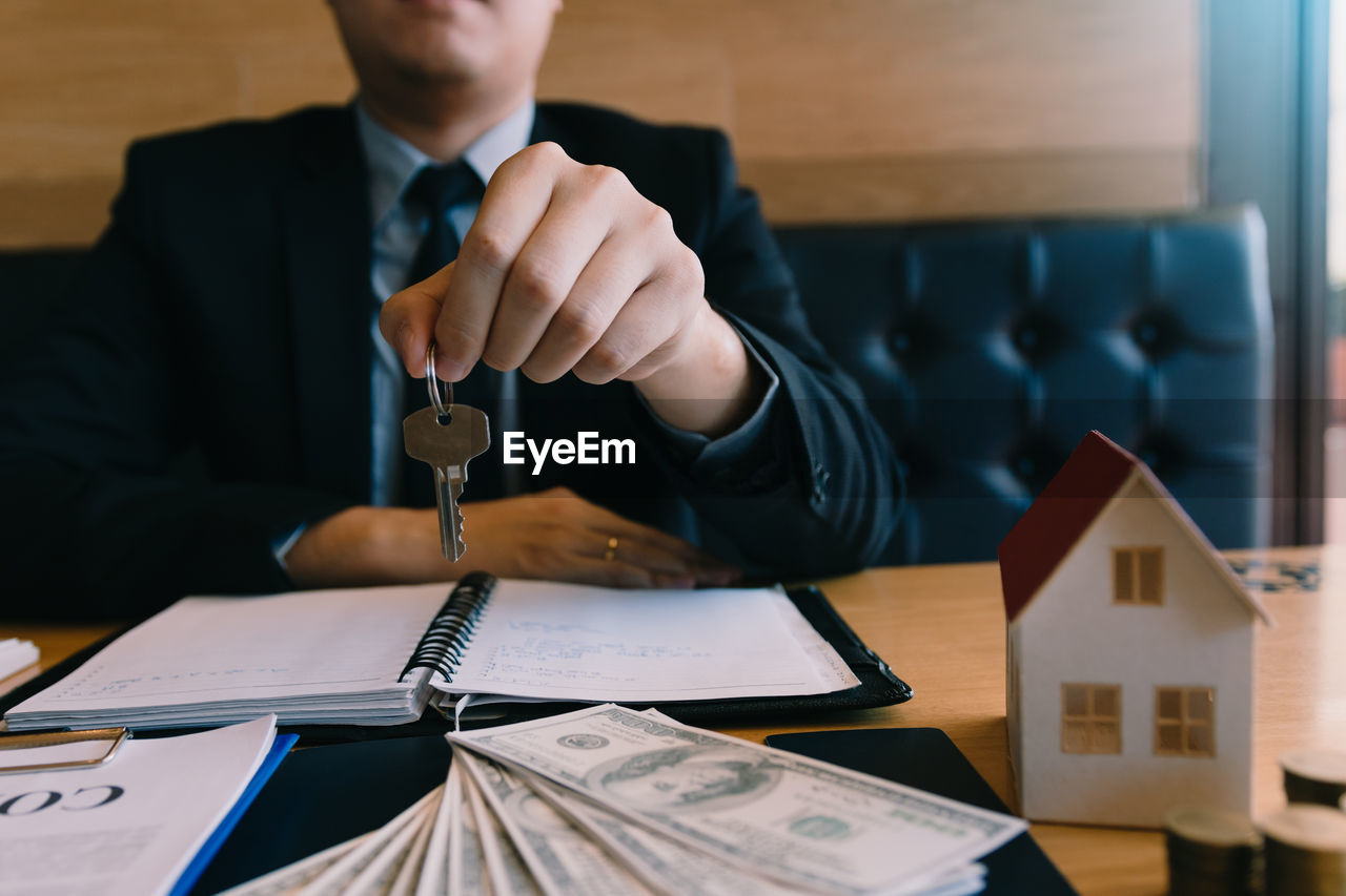 Midsection of man holding key over paper at table