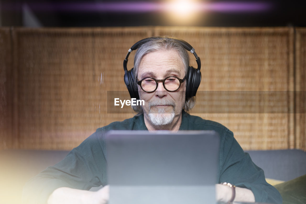 Senior man with headphones using tablet