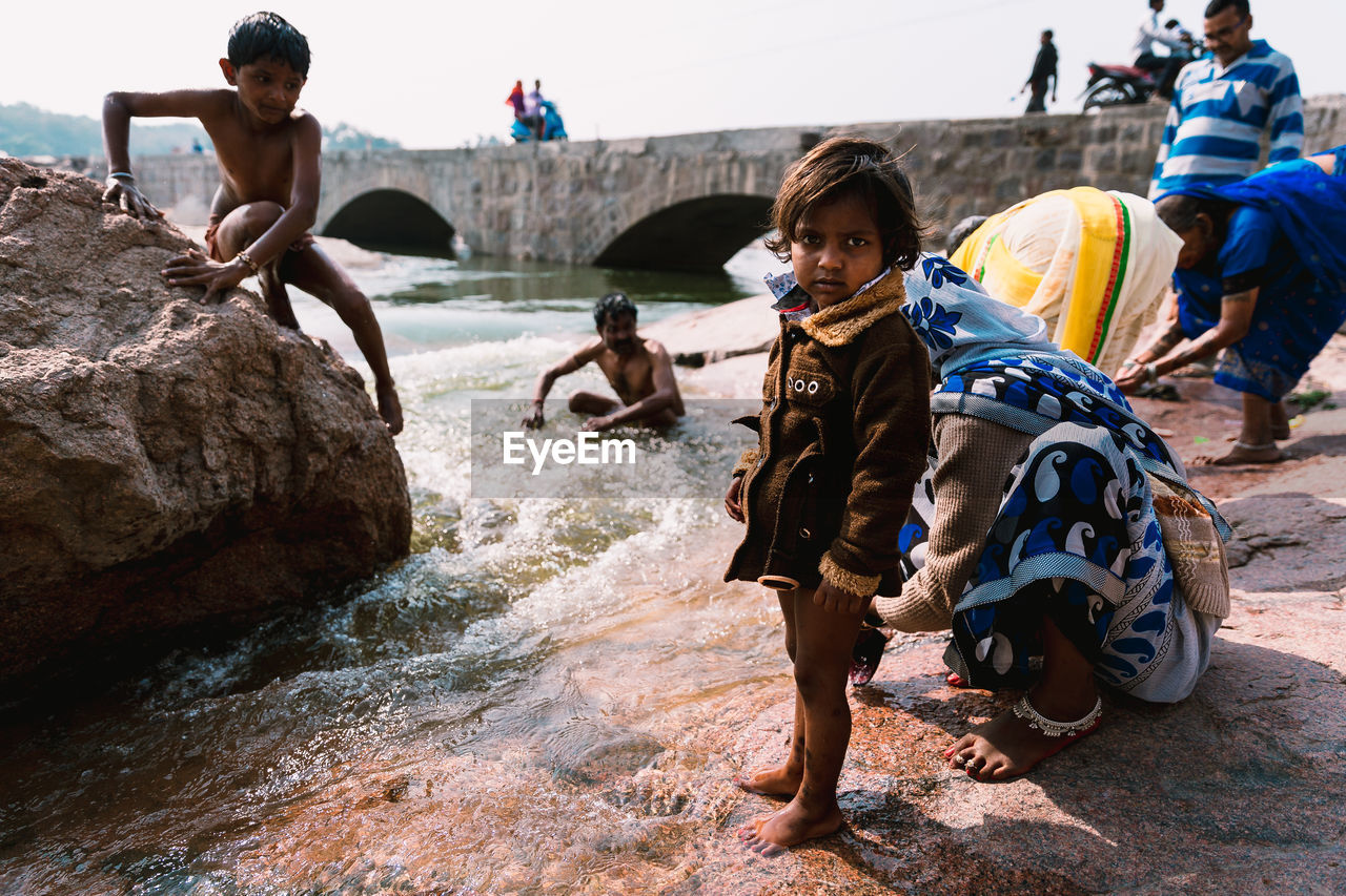 GROUP OF PEOPLE ON ROCK AGAINST WATER