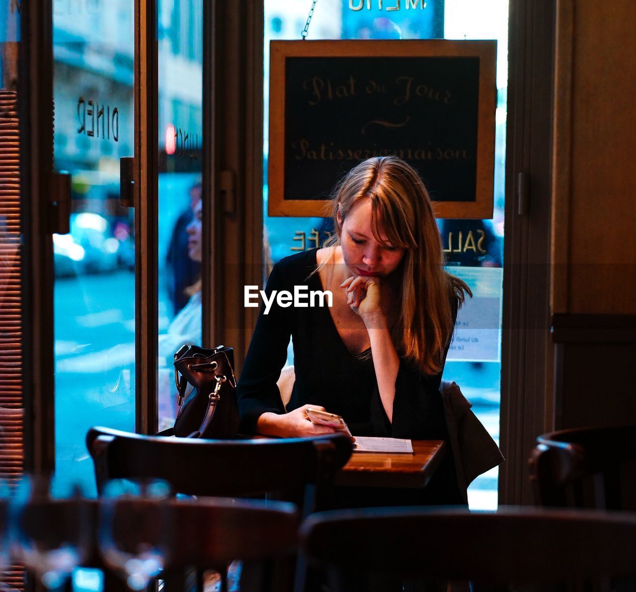 PORTRAIT OF WOMAN SITTING IN RESTAURANT AT CAFE