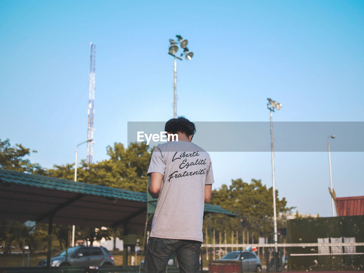 Rear view of man standing against clear blue sky