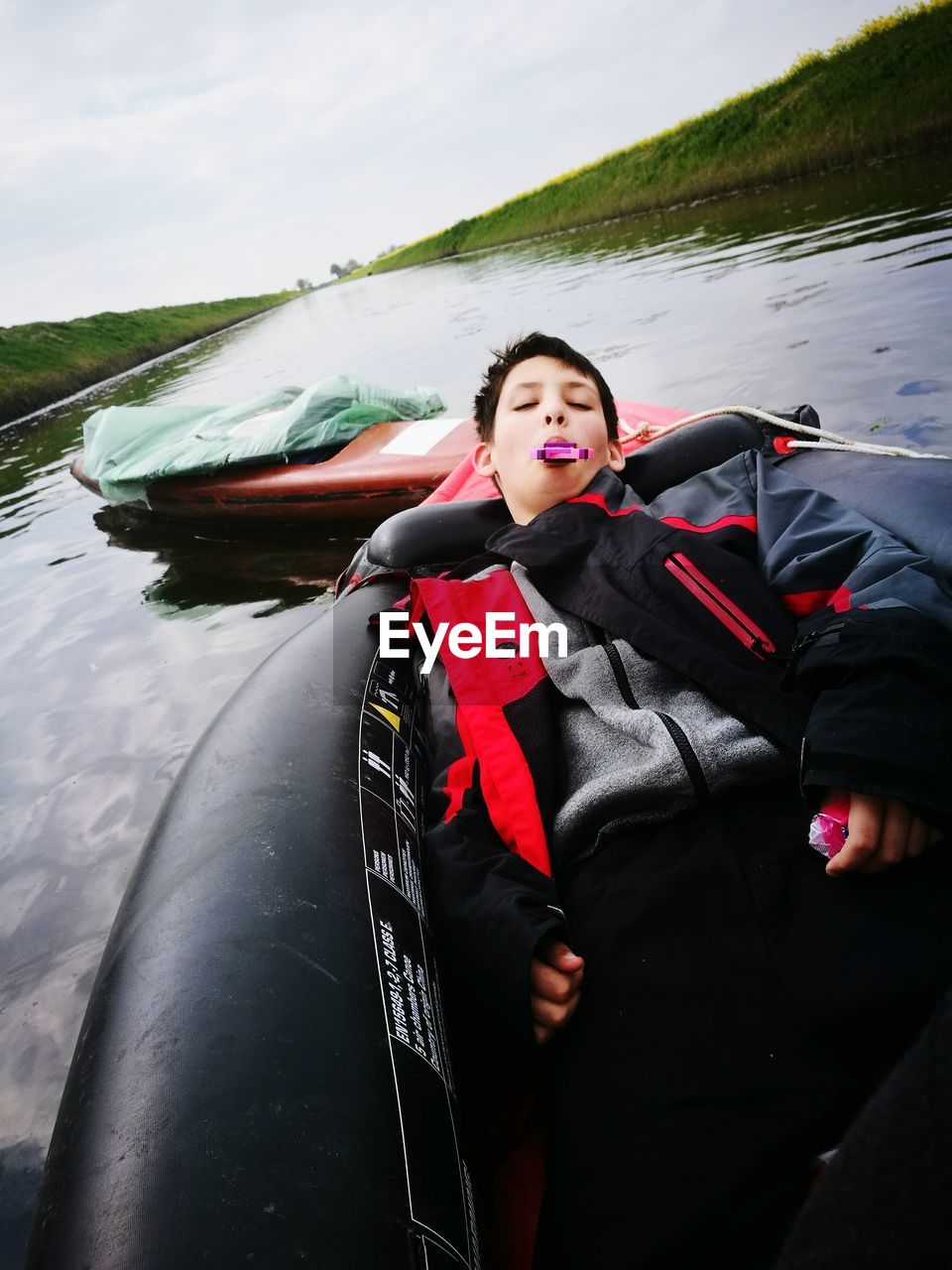 High angle view of boy with candy lying on inflatable raft in river