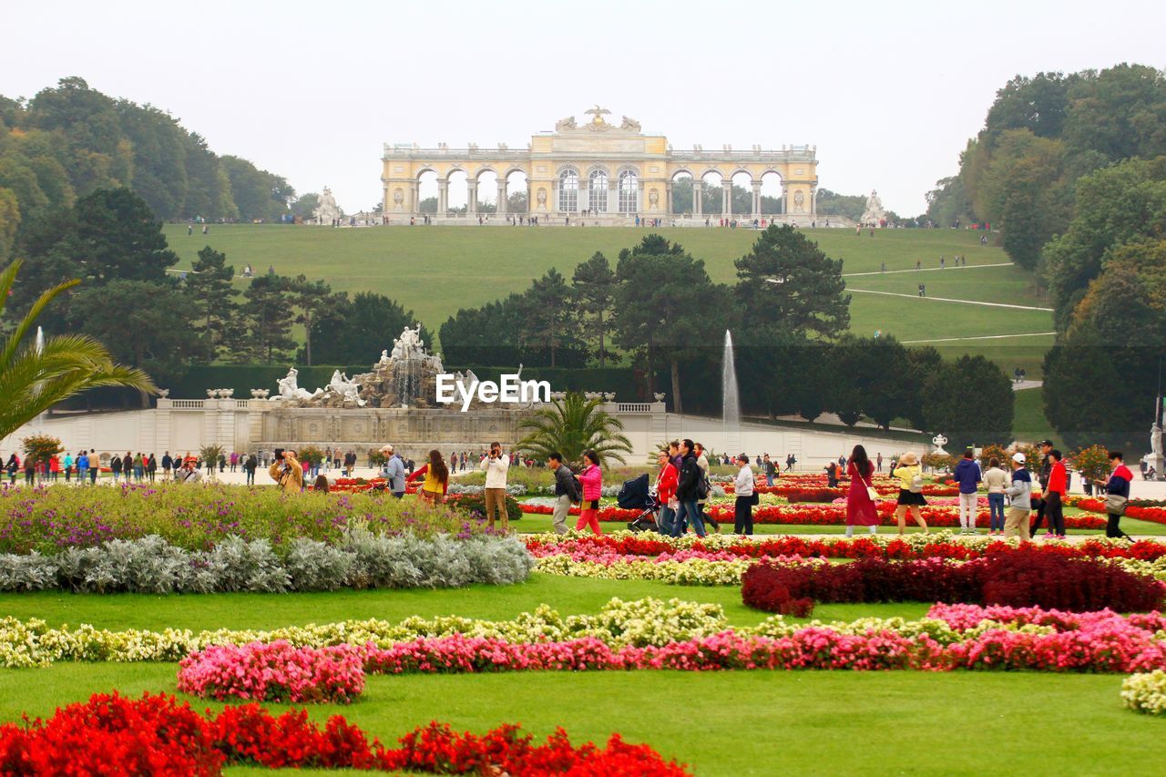 People at neptunbrunnen against schonbrunn palace garden gloriette