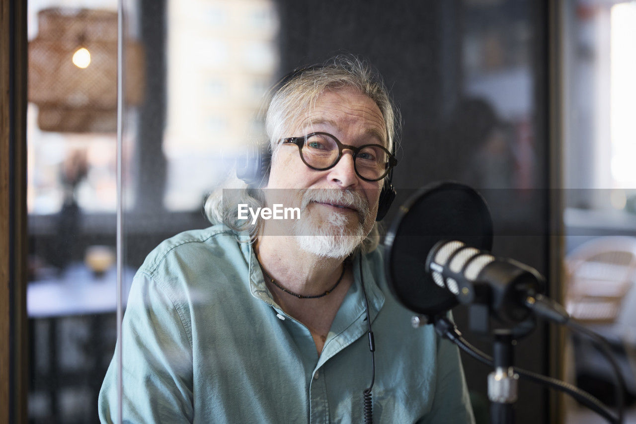 Mature man sitting and hosting podcast or radio show or podcast