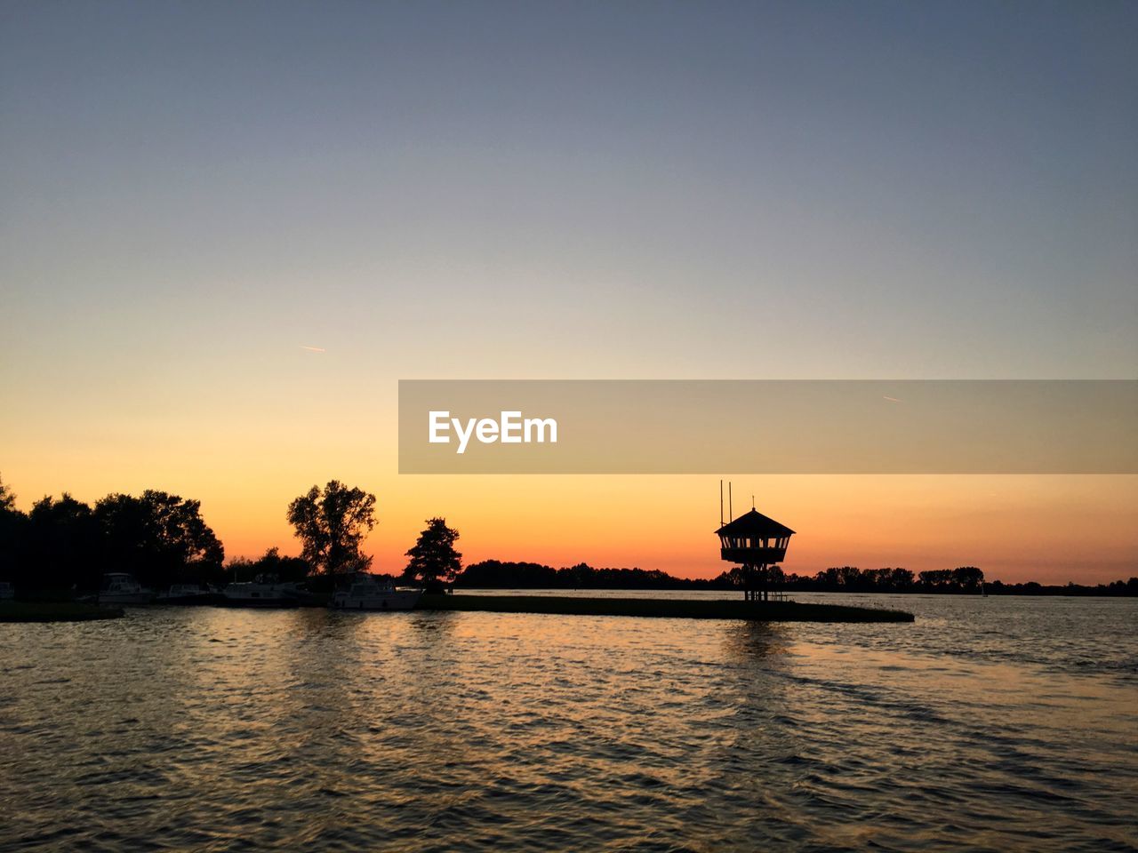 SILHOUETTE TREES BY LAKE AGAINST SKY DURING SUNSET