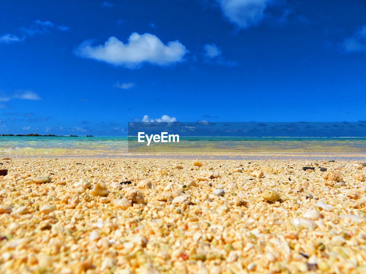 SURFACE LEVEL VIEW OF PEBBLE BEACH AGAINST BLUE SKY