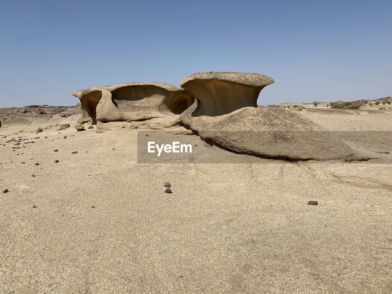 ROCK FORMATIONS ON SAND AGAINST CLEAR SKY