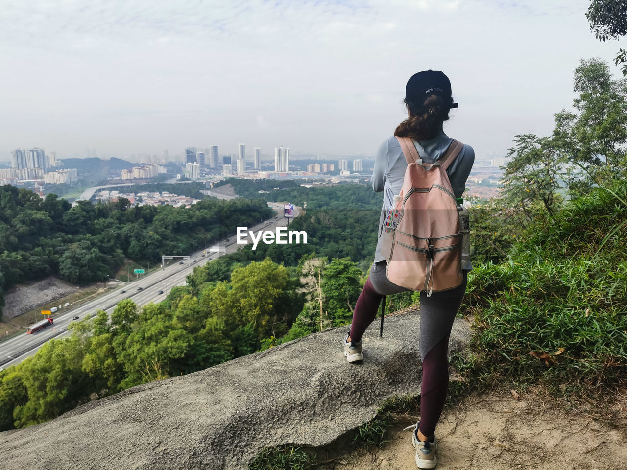 Rear view of woman standing on rock against sky