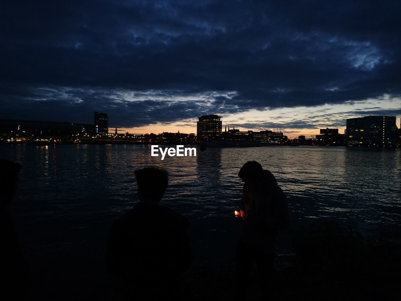 REAR VIEW OF MEN ON CITY AT WATERFRONT