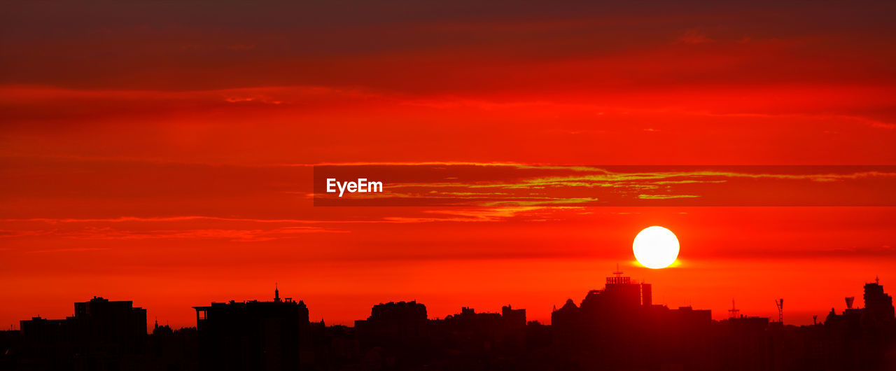 Panorama of silhouettes of buildings of the city of a red sunrise, red landscape of night kyiv.