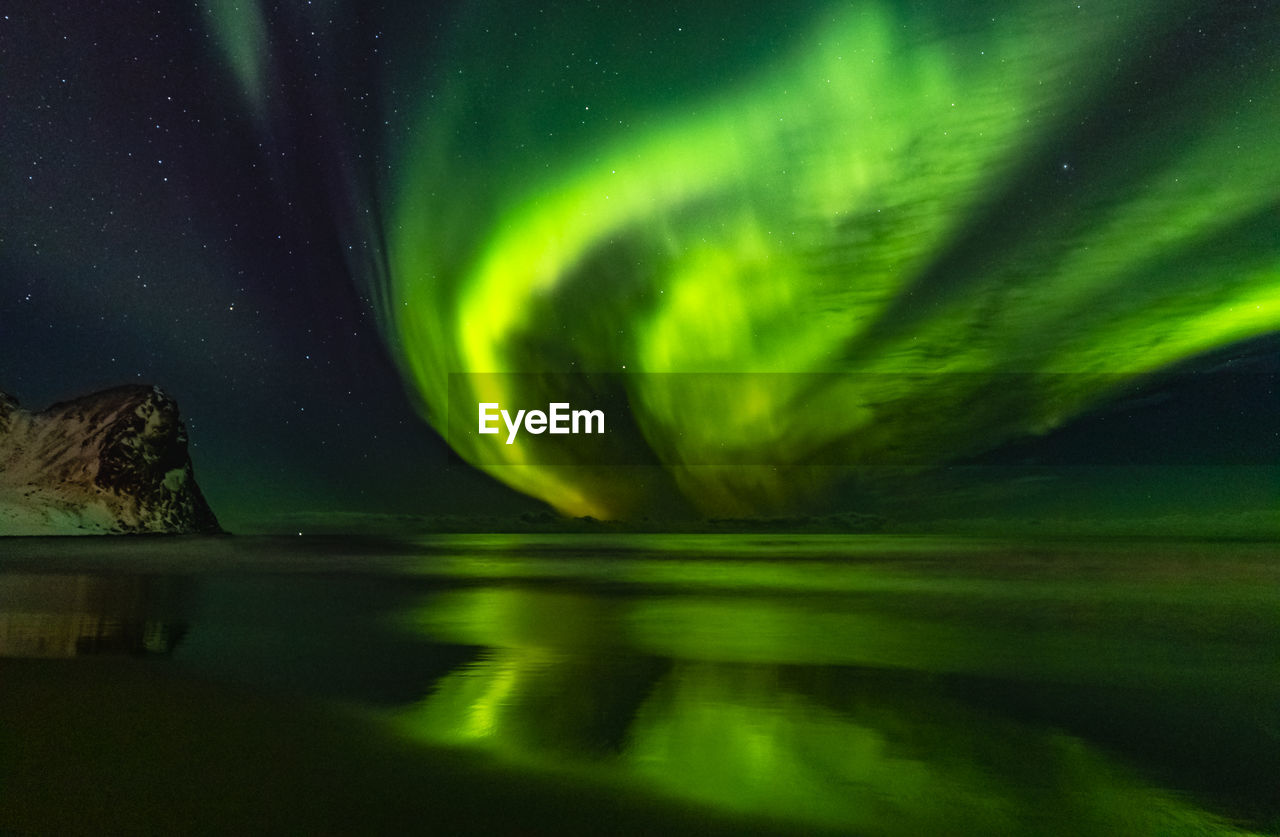 Scenic view of aurora borealis reflecting on lake against sky at night