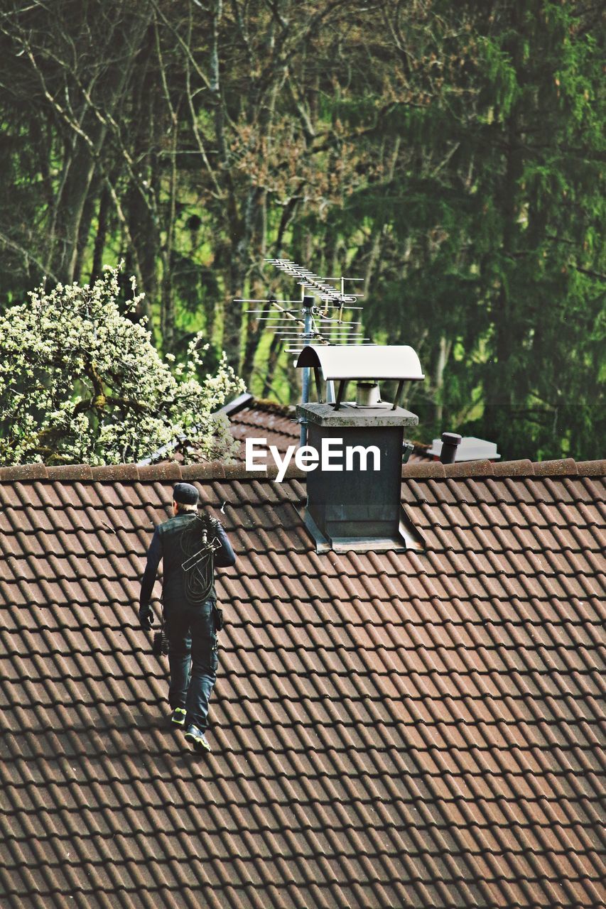 High angle view of chimney sweep walking on roof