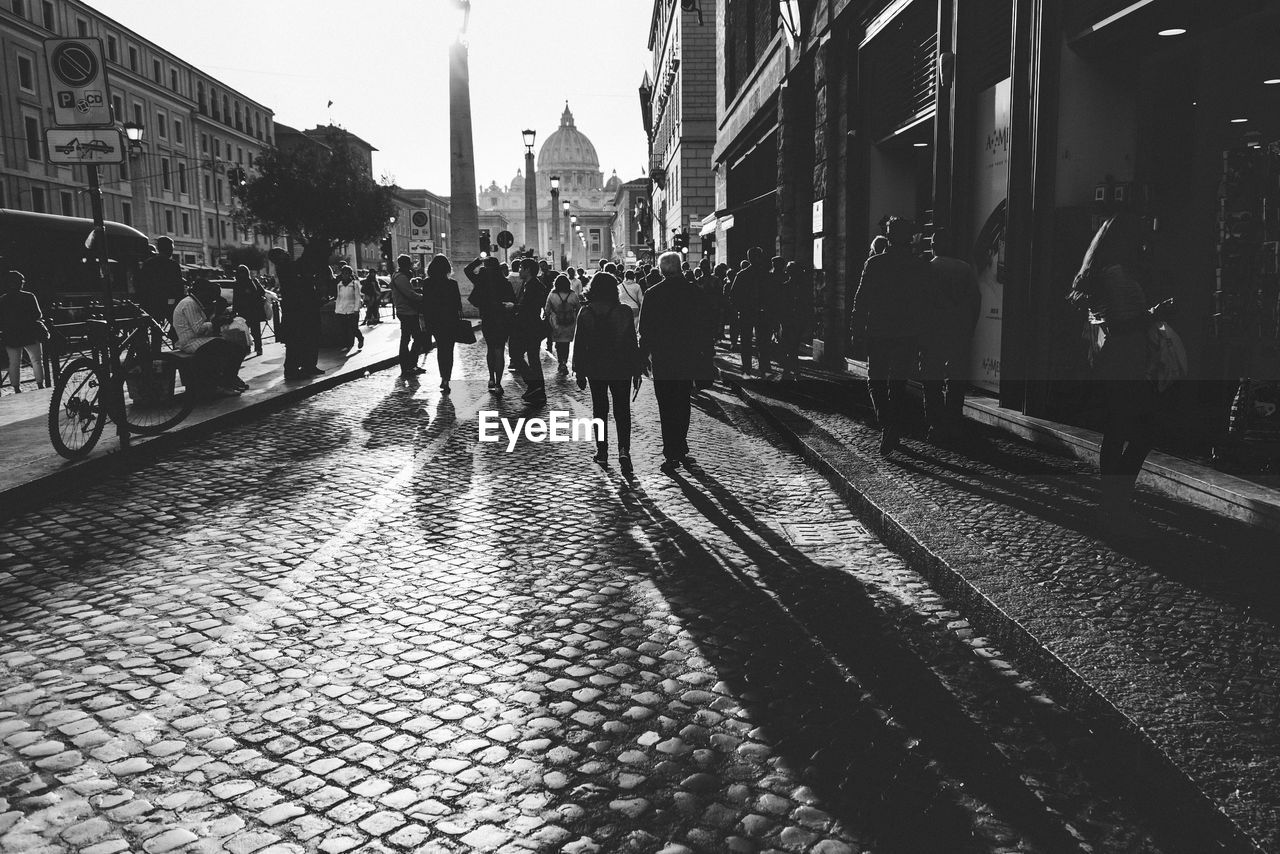 GROUP OF PEOPLE WALKING ON ROAD IN CITY