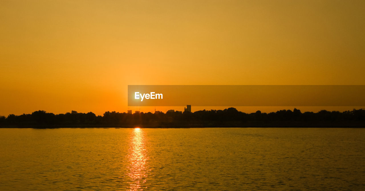 Scenic view of lake against clear sky during sunset