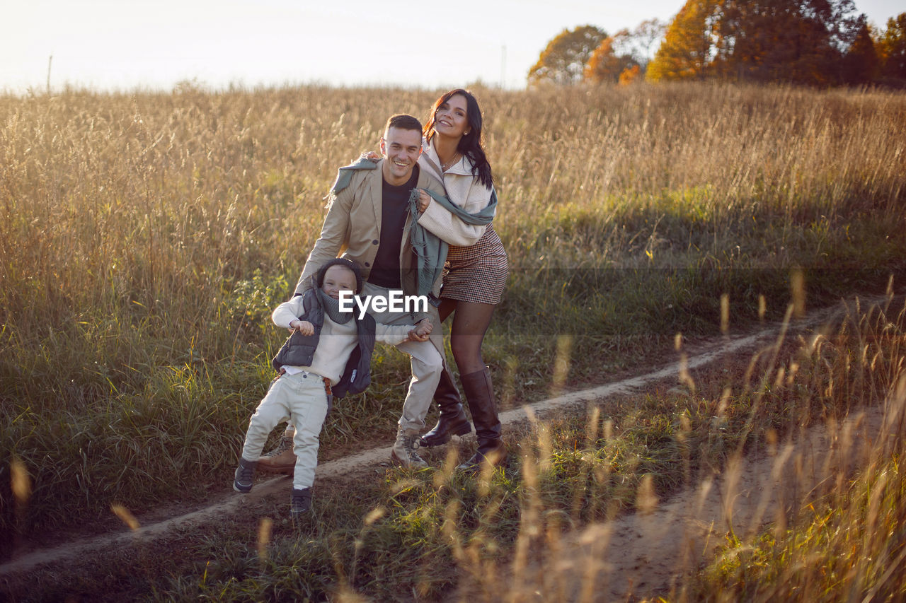 Stylish family with a boy child on a field in the dry grass in autumn