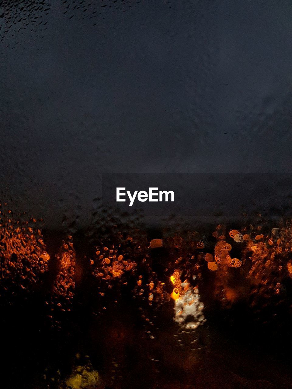 CLOSE-UP OF WET ILLUMINATED ROAD DURING RAINY SEASON