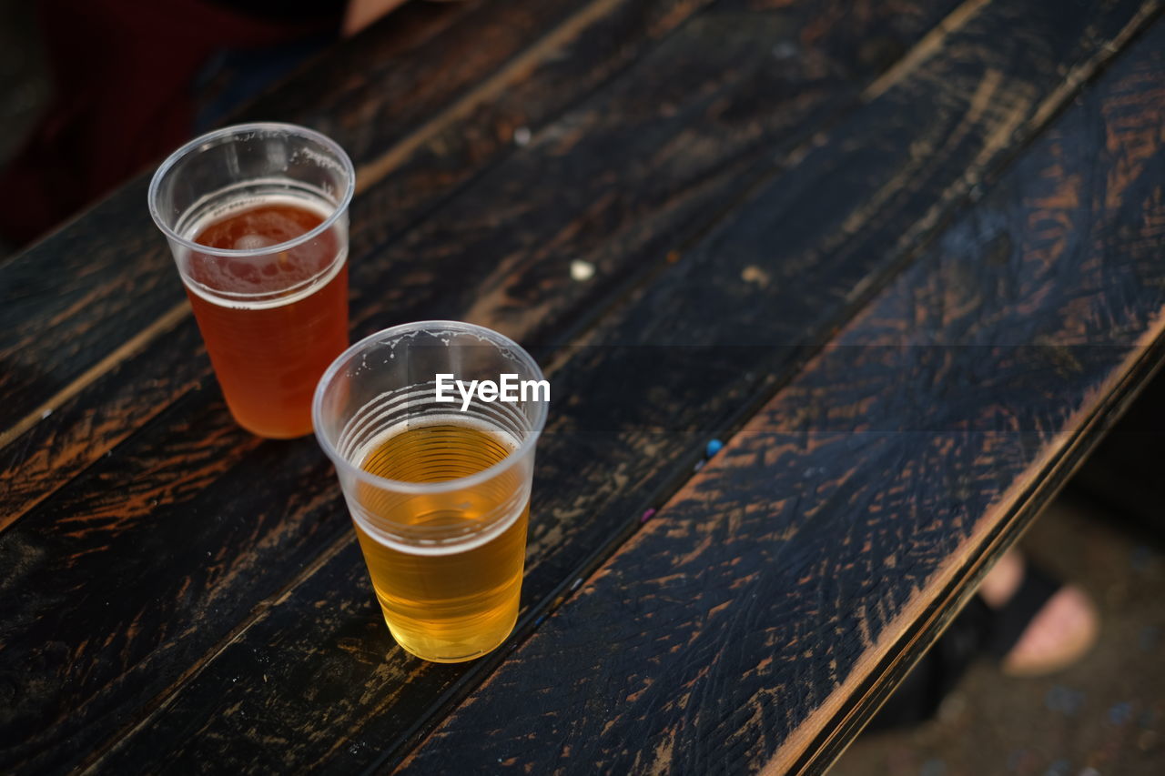 High angle view of beer glasses on wooden table at sidewalk cafe