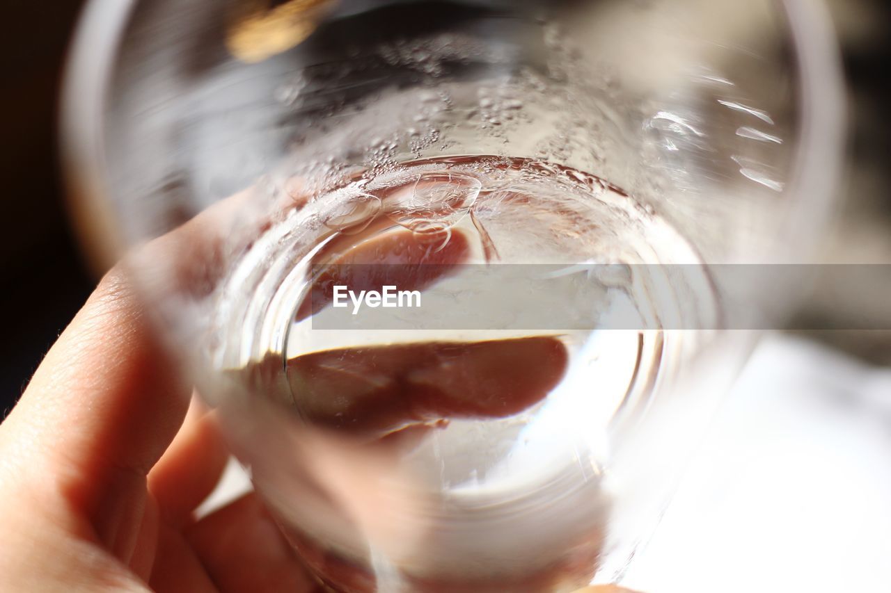 Cropped hand holding glass of water at home