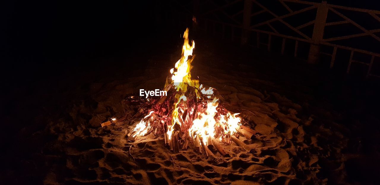 CLOSE-UP OF ILLUMINATED BONFIRE AT NIGHT