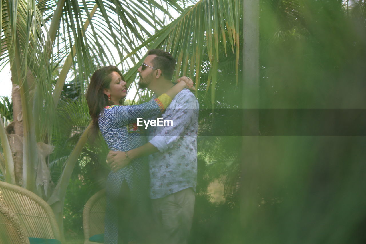 Young couple embracing while standing amidst trees