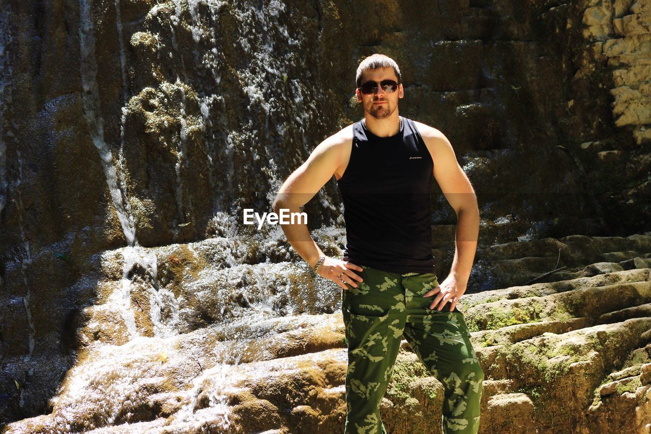 PORTRAIT OF YOUNG MAN STANDING ON ROCKS