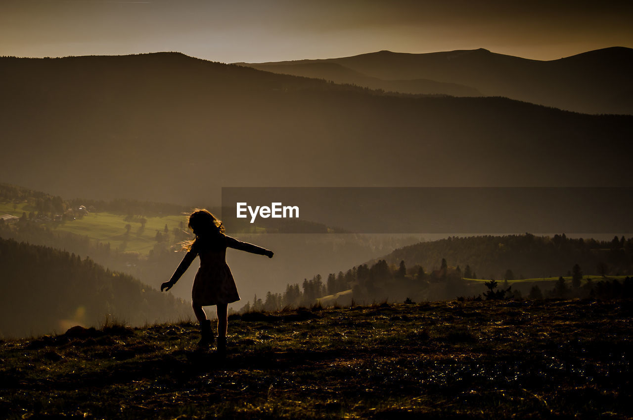 FULL LENGTH OF SILHOUETTE WOMAN STANDING ON FIELD AGAINST SKY