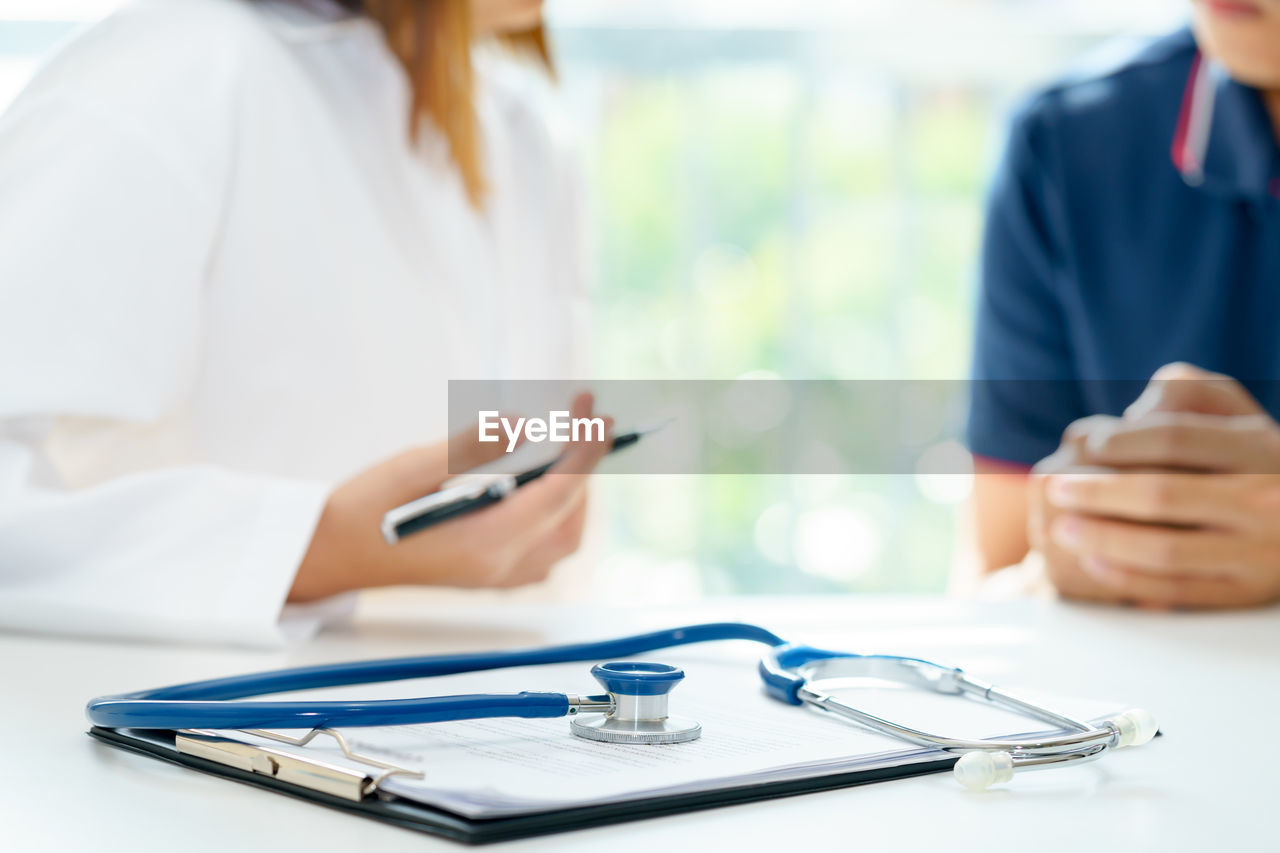 Midsection of female doctor talking with patient in clinic