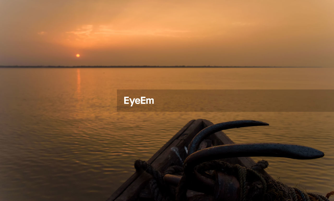 water, sunset, sky, sea, beauty in nature, scenics - nature, tranquility, nature, evening, horizon over water, tranquil scene, horizon, transportation, dusk, no people, reflection, vehicle, mode of transportation, idyllic, ocean, nautical vessel, cloud, orange color, outdoors, coast, beach, sun, shore, land, travel destinations, dramatic sky, non-urban scene, sunlight, travel, seascape