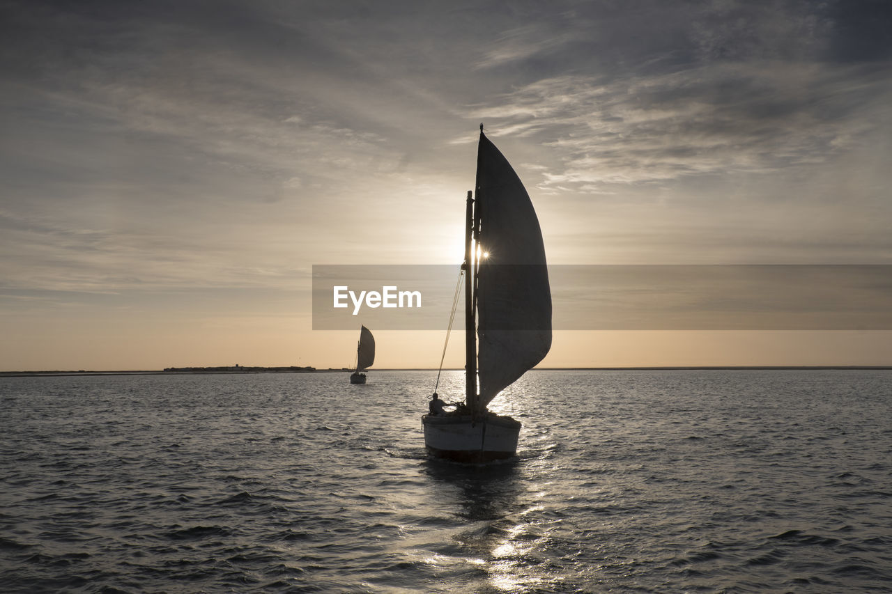 Sailboat on sea against sky during sunset