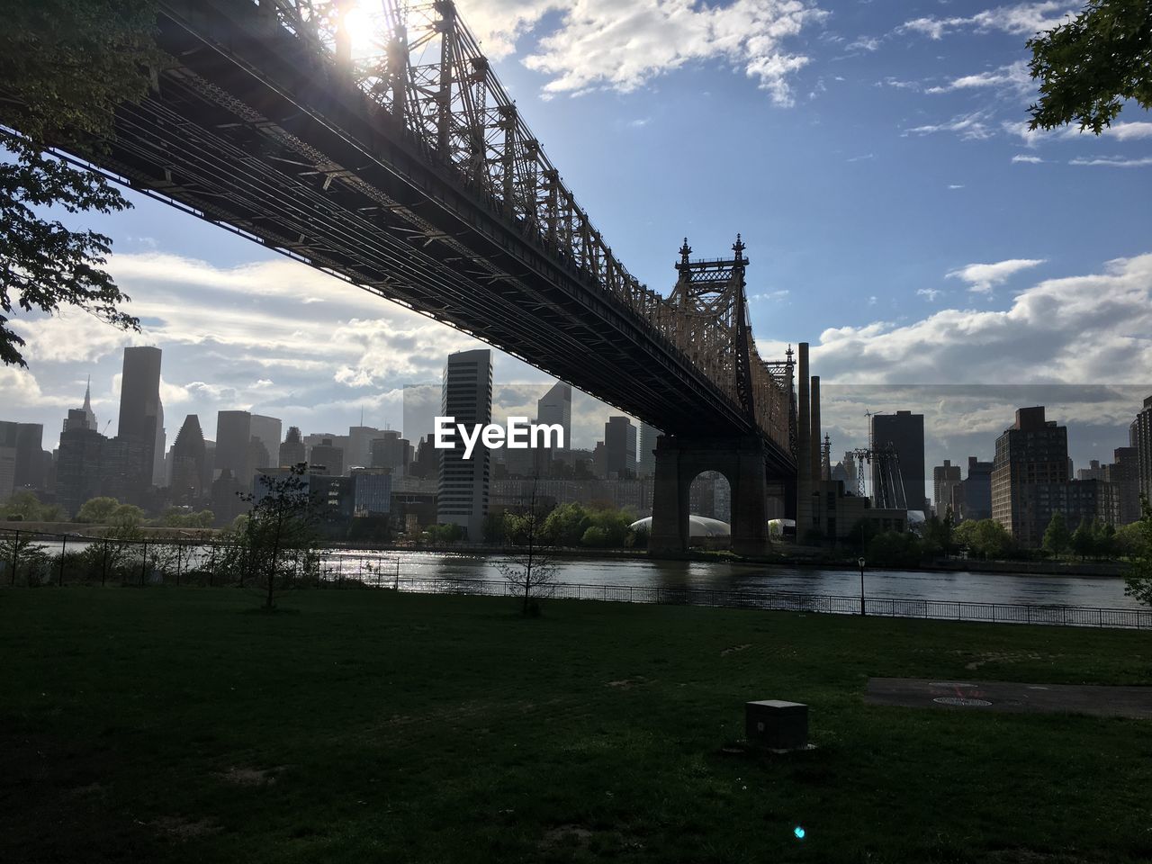 BRIDGE OVER RIVER AMIDST BUILDINGS IN CITY AGAINST SKY