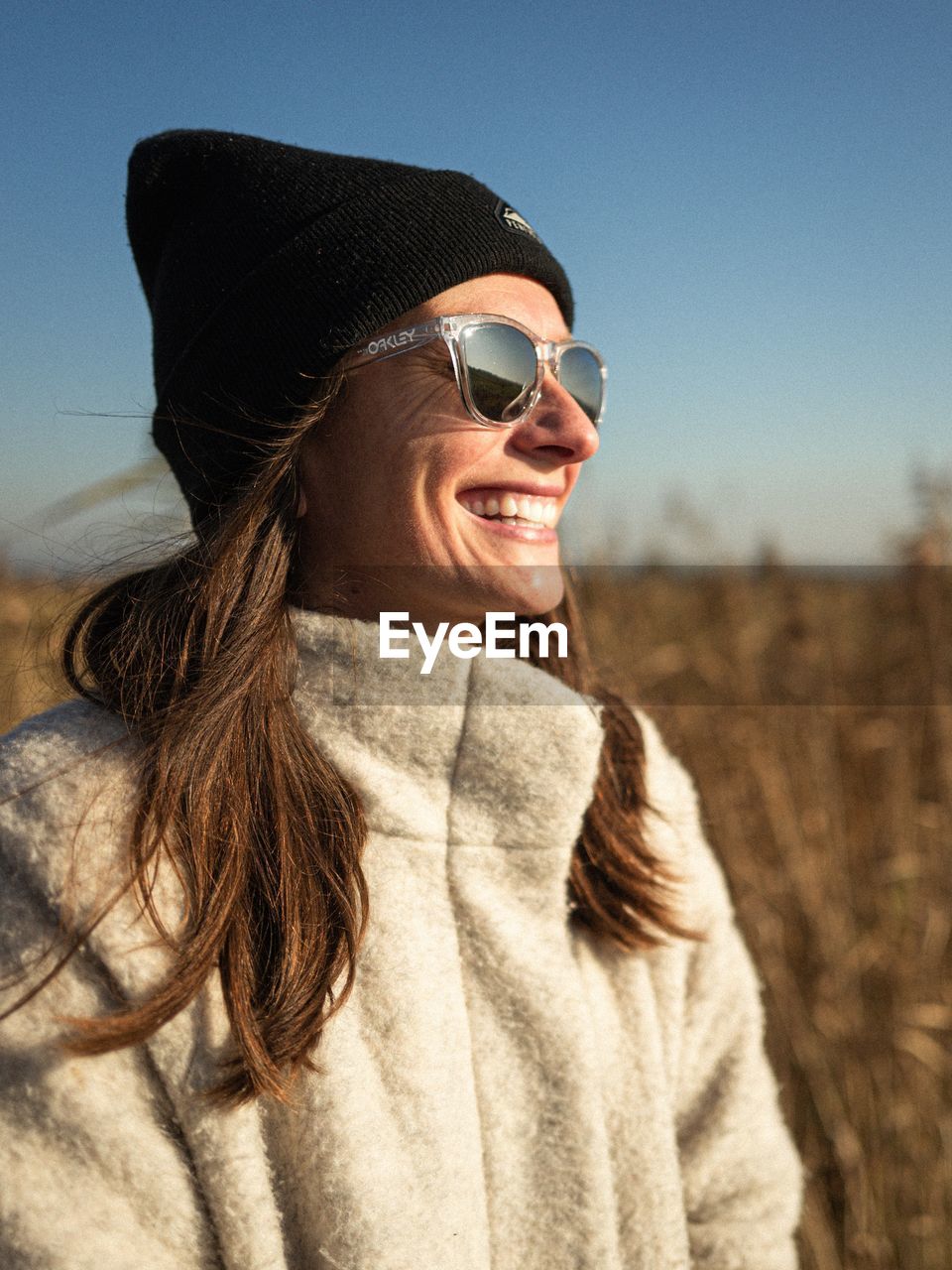 PORTRAIT OF A SMILING YOUNG WOMAN AGAINST THE SKY