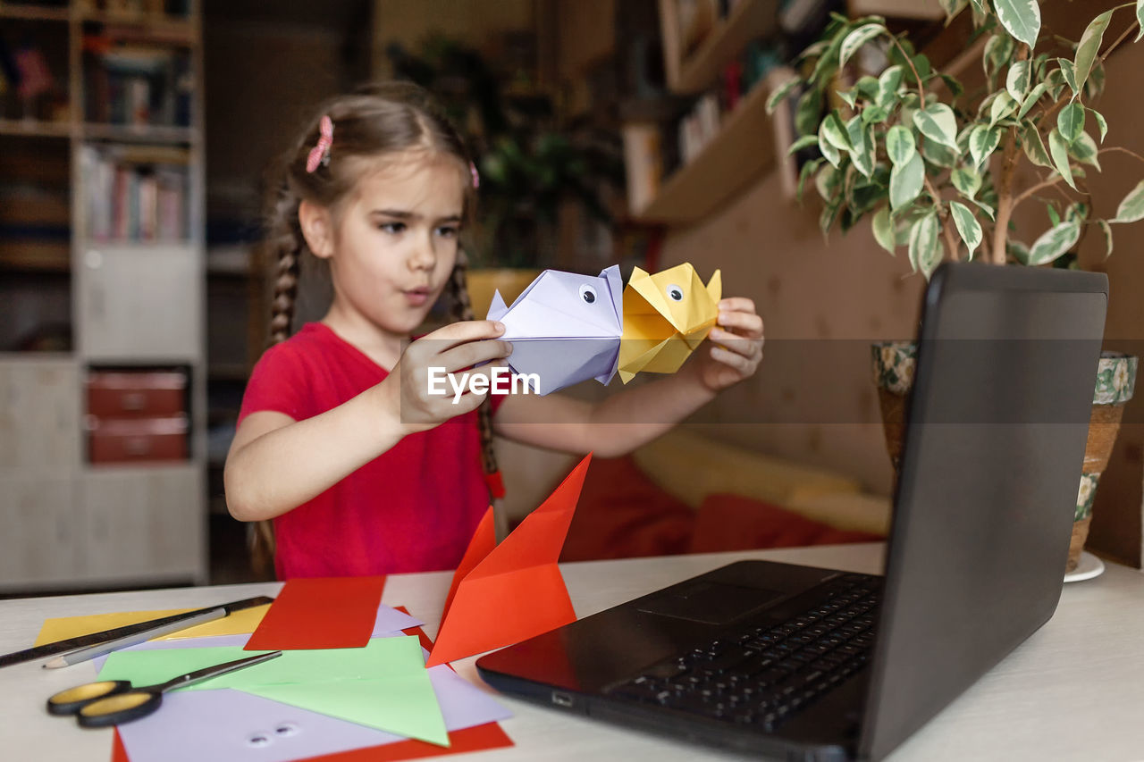 Close-up of girl holding origami at home
