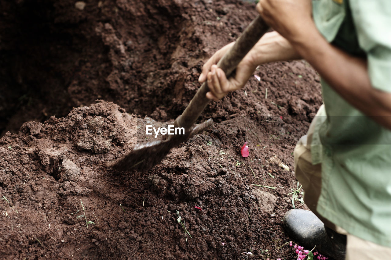 Low section of man digging mud