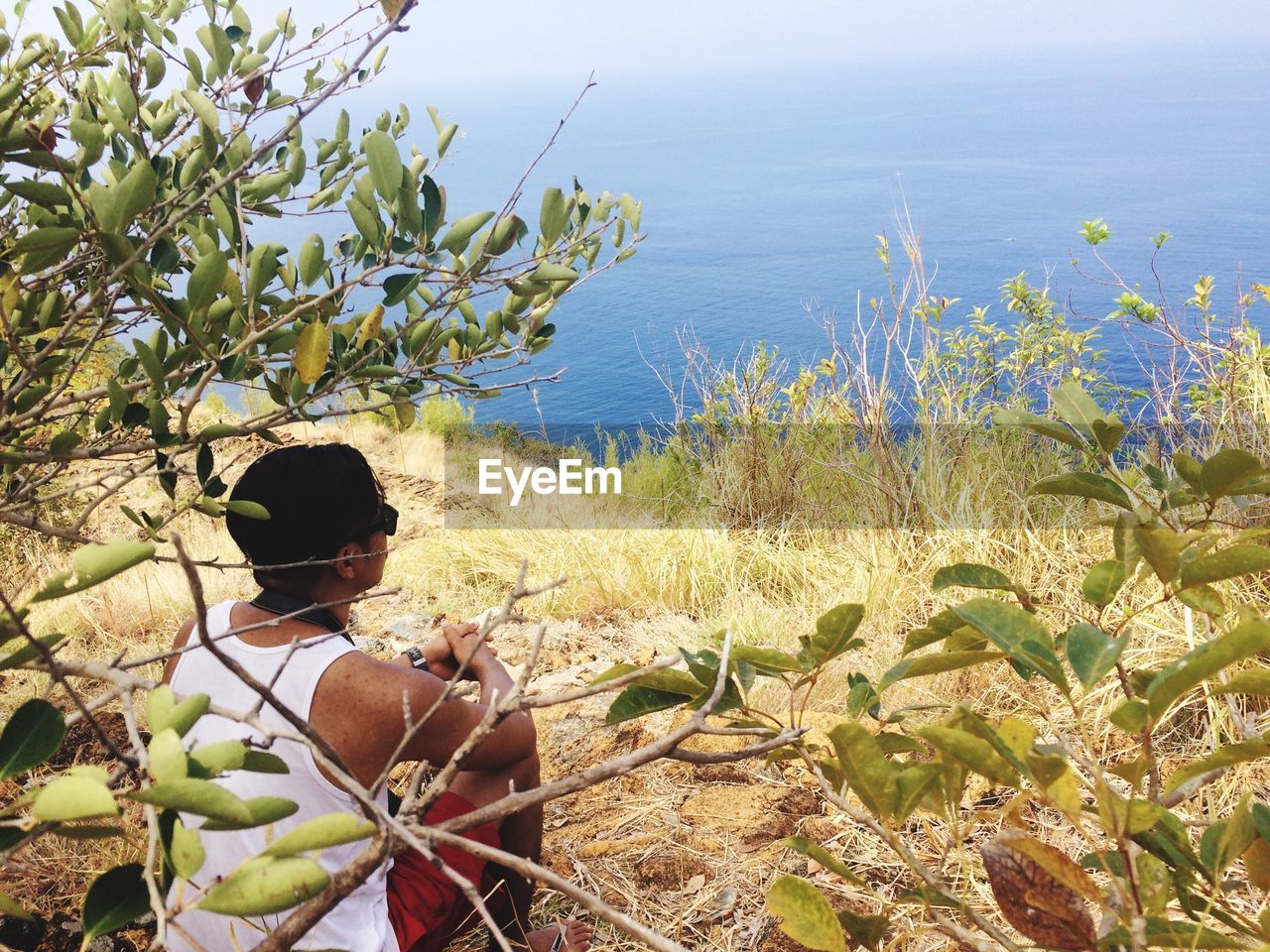 Man sitting on hill by sea